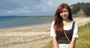 A female international student standing on a beach.